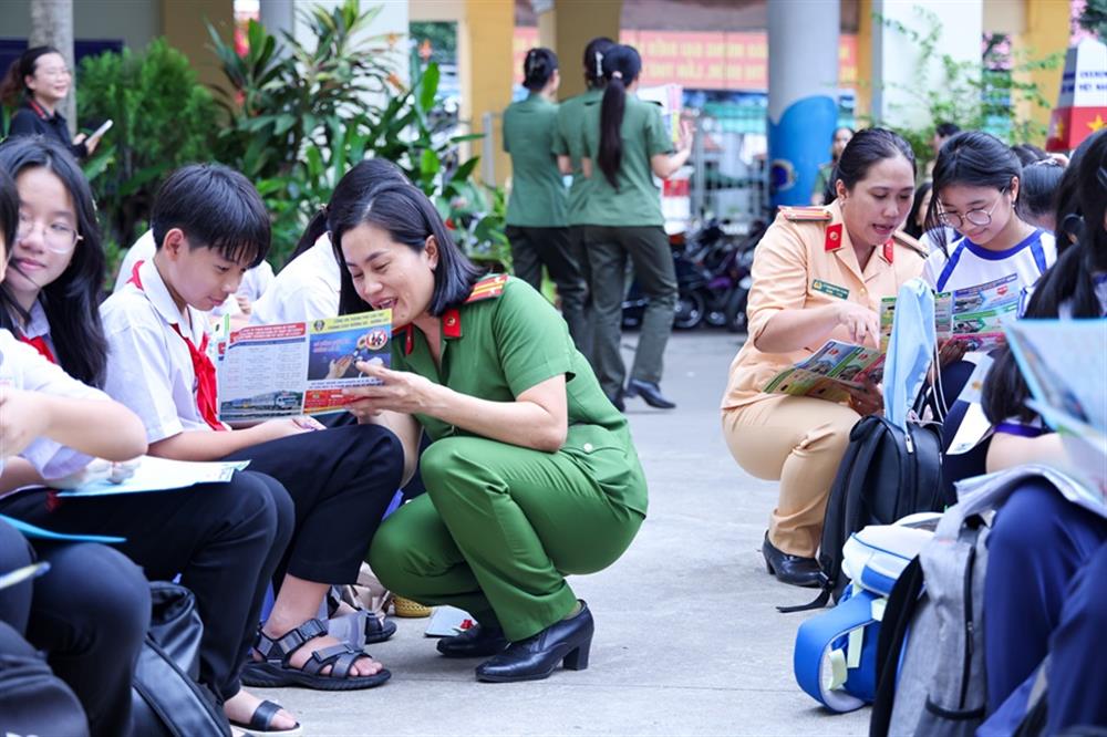 Cán bộ, chiến sĩ phát tờ rơi tuyên truyền đến các em học sinh.