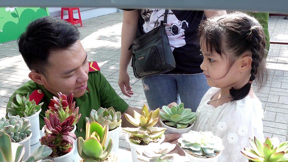 Cán bộ, chiến sĩ trẻ Công an thành phố trao chậu cây cho một bé thiếu nhi đến tham gia chương trình.