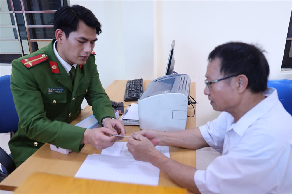 Cán bộ Công an xã bàn giao căn cước cho người dân.