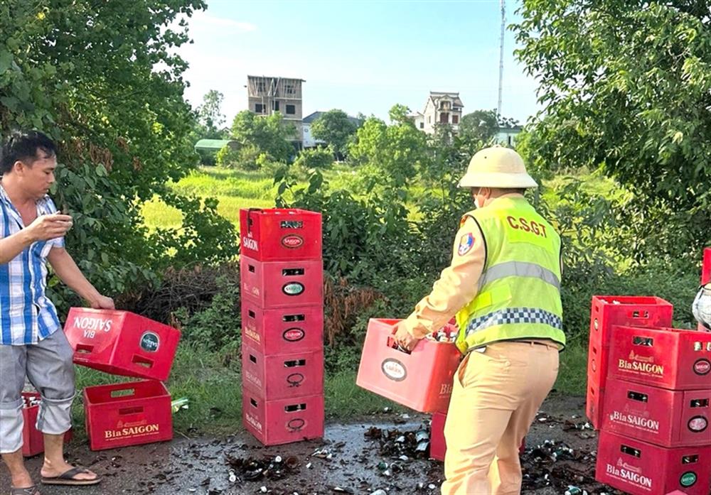 Tổ CSGT đường bộ số 5 cùng người dân giúp đỡ lái xe thu dọn số bia chai bị vỡ trên đường.