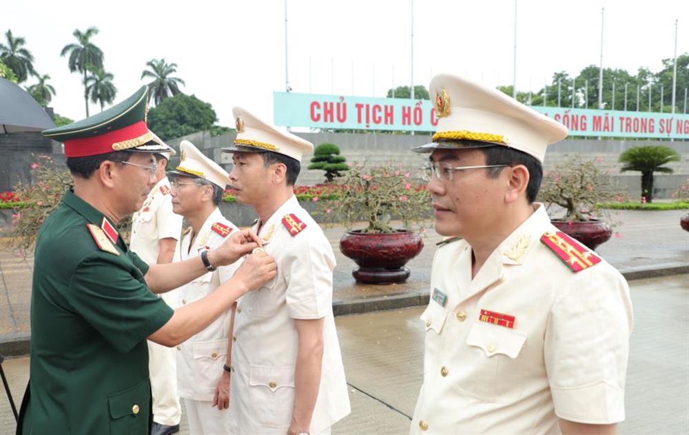 Đồng chí Thiếu tướng Đinh Quốc Hùng, Chính ủy Bộ Tư lệnh bảo vệ Lăng Chủ tịch Hồ Chí Minh trao tặng, gắn Huy hiệu Bác Hồ cho các đồng chí lãnh đạo Công an tỉnh Hà Nam.