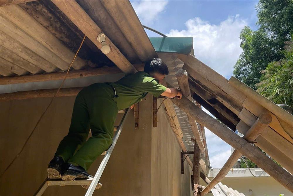 Cán bộ Công an xã Hữu Lũng tháo dỡ phần mái nhà bị ảnh hưởng do sạt lở để bảo đảm an toàn cho hộ dân.