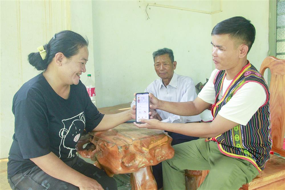 Anh Điểu Luân (bìa phải), Tổ trưởng Tổ bảo vệ an ninh ấp 7, xã Lộc Hòa, huyện Lộc Ninh hướng dẫn người dân trong ấp kích hoạt tài khoản ĐDĐT.