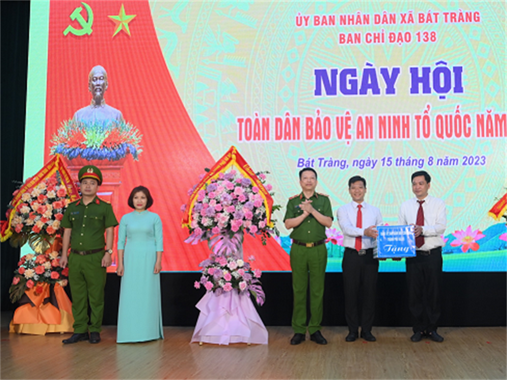 Đại tá Nguyễn Hồng Ky, Phó Giám đốc Công an thành phố Hà Nội trao hoa và quà tặng đại diện chính quyền và nhân dân xã Bát Tràng.