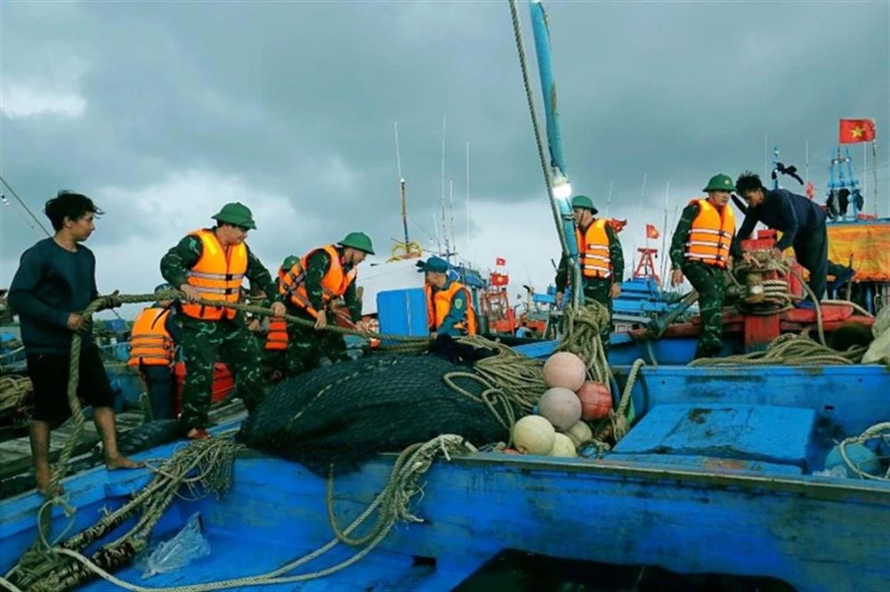 Cán bộ, chiến sĩ lực lượng vũ trang huyện Hải Hậu, tỉnh Nam Định giúp ngư dân chằng buộc tàu, thuyền tại cảng cá Ninh Cơ.